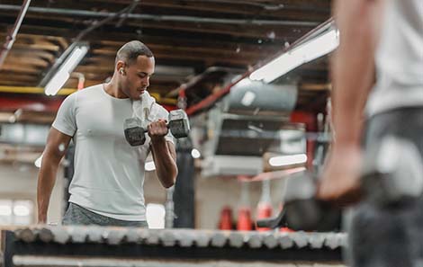 man-krachttraining-voor-spiegel-met-dumbbells.jpg