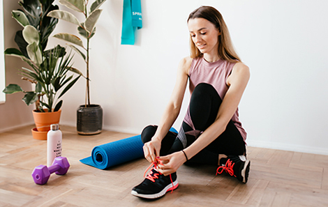 vrouw-schoenen-strikken-en-thuis-trainen-op-fitnessmat-met-dumbbells.jpg