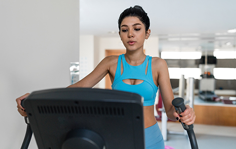 vrouw-trainend-op-crosstrainer-in-huiskamer-kijkend-naar-console.jpg